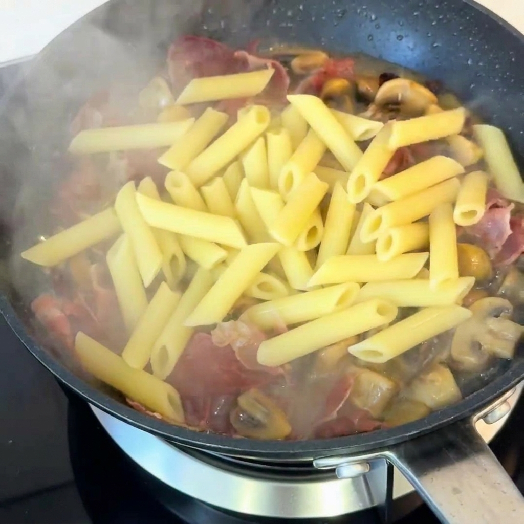 Penne saltate in padella con funghi e prosciutto, condite con pepe nero.