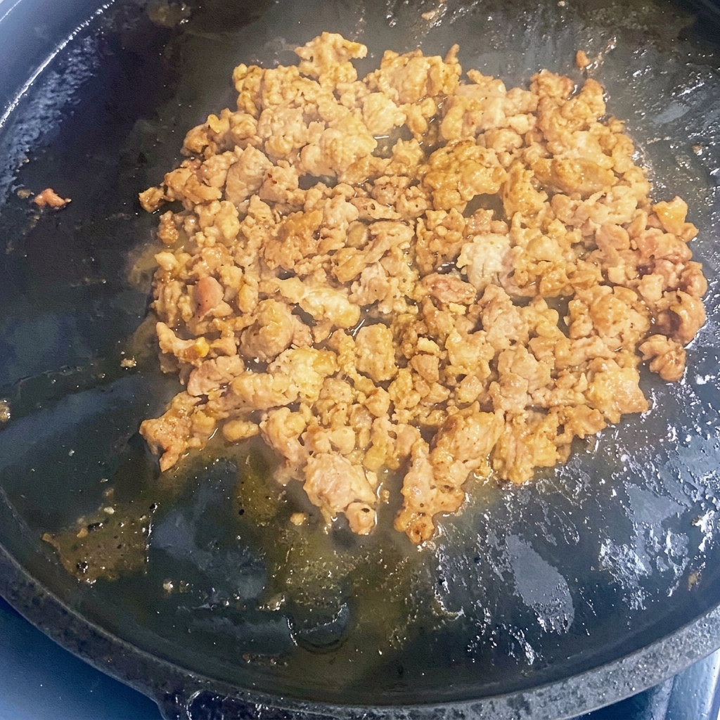 Carne macinata in rosolatura in una padella in ghisa.