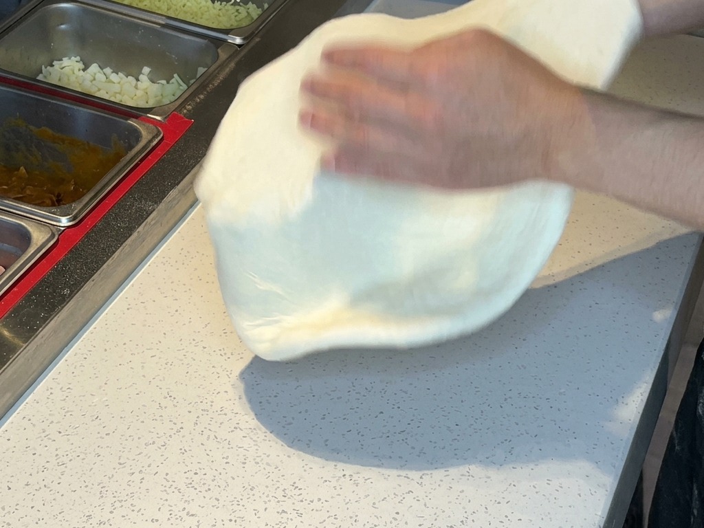 Due mani che sollevano e passano da una parte allaltra limpasto steso.