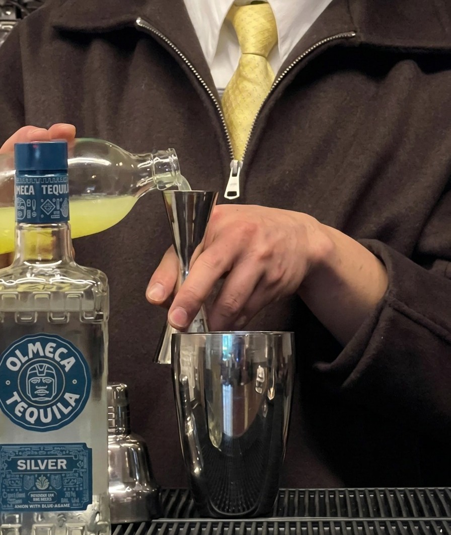Succo di lime fresco versato in un jigger sopra uno shaker per cocktail.