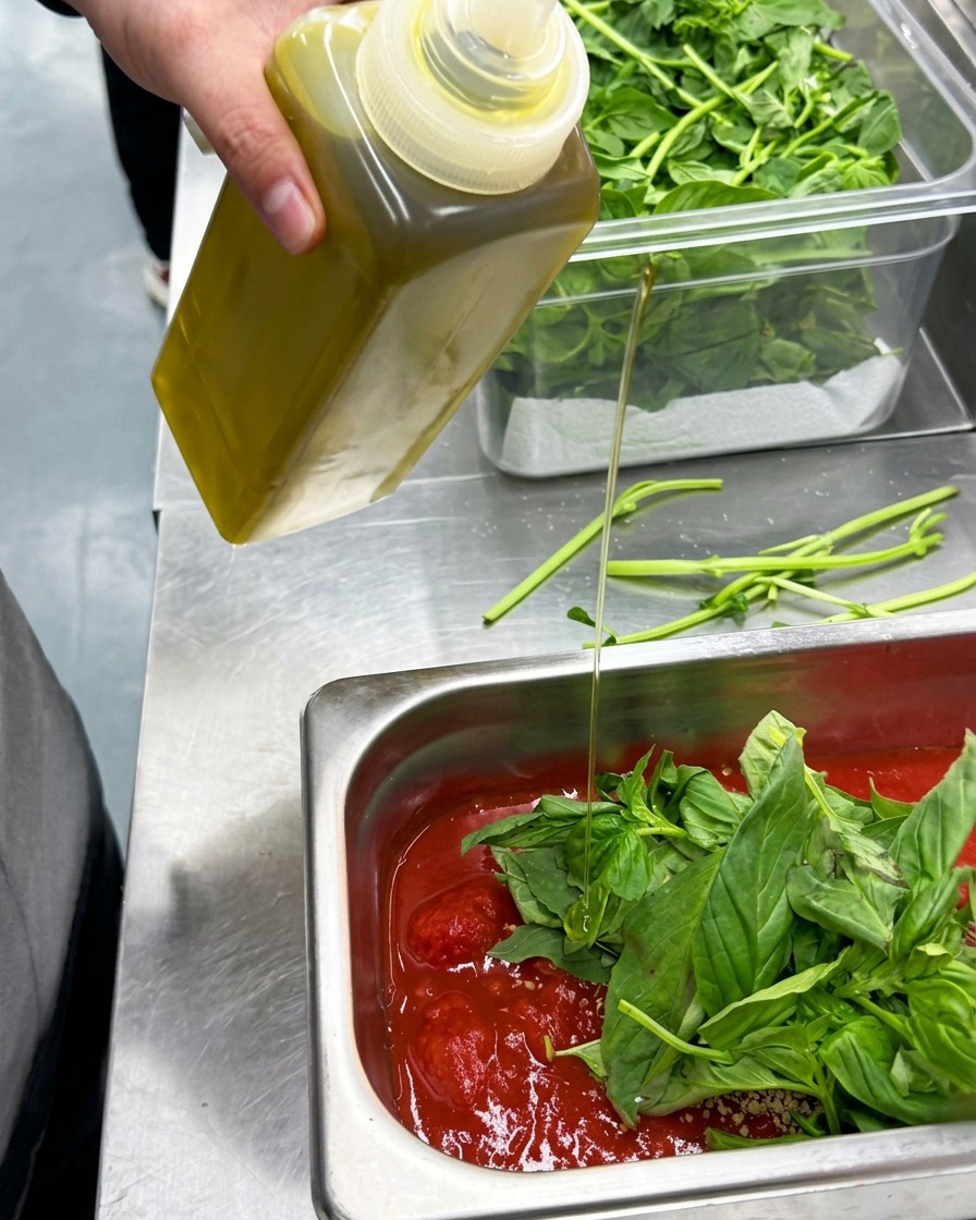 Olio doliva versato da una bottiglia nel contenitore con gli ingredienti della salsa.