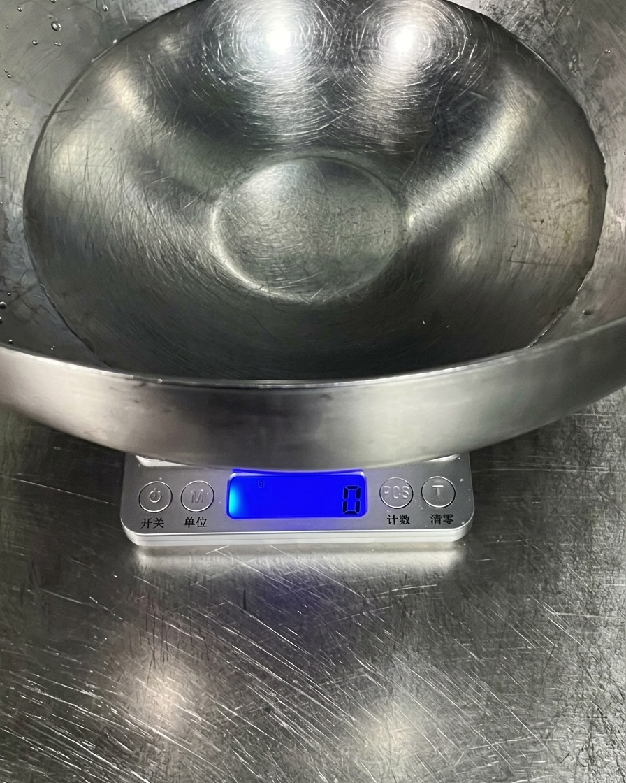 Una ciotola dacciaio inox su una bilancia da cucina contenente acqua fredda.