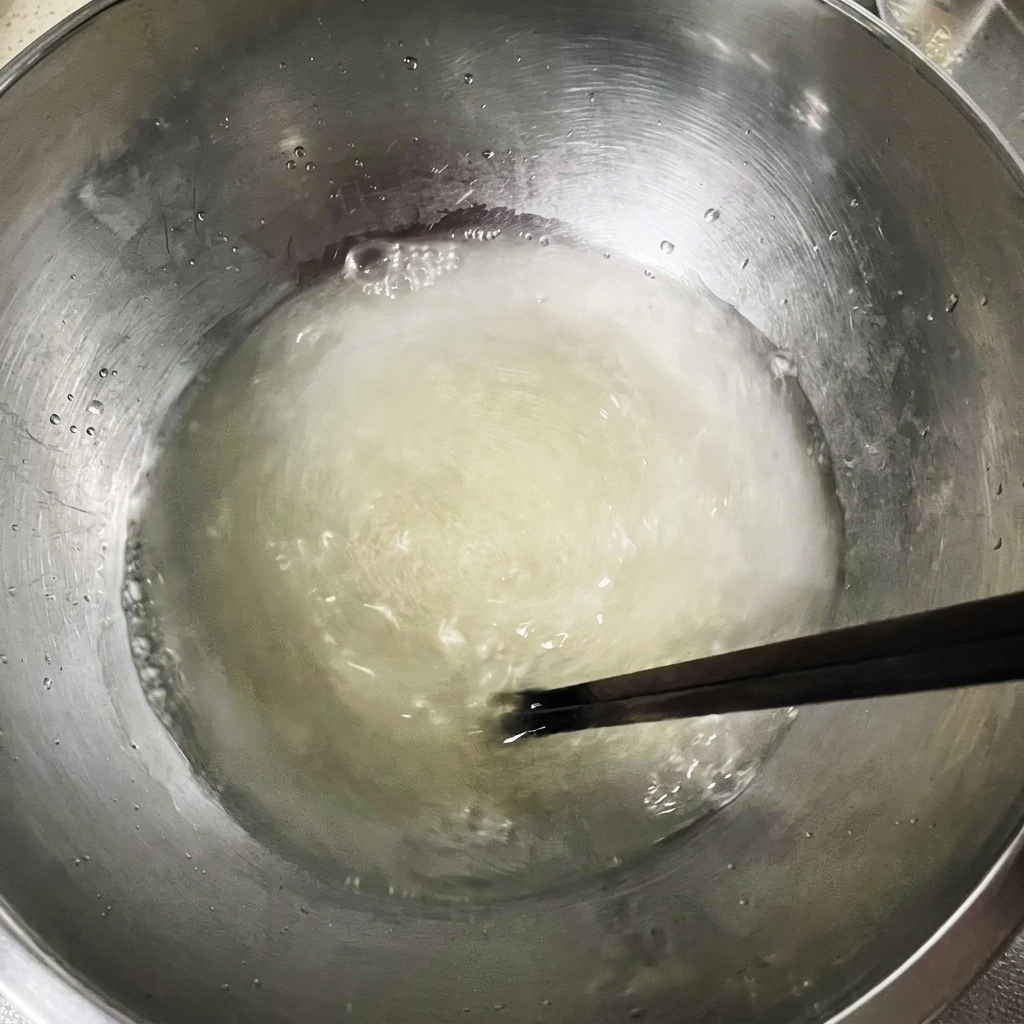 Miscela di acqua, lievito e sale mescolata con bacchette in una ciotola.
