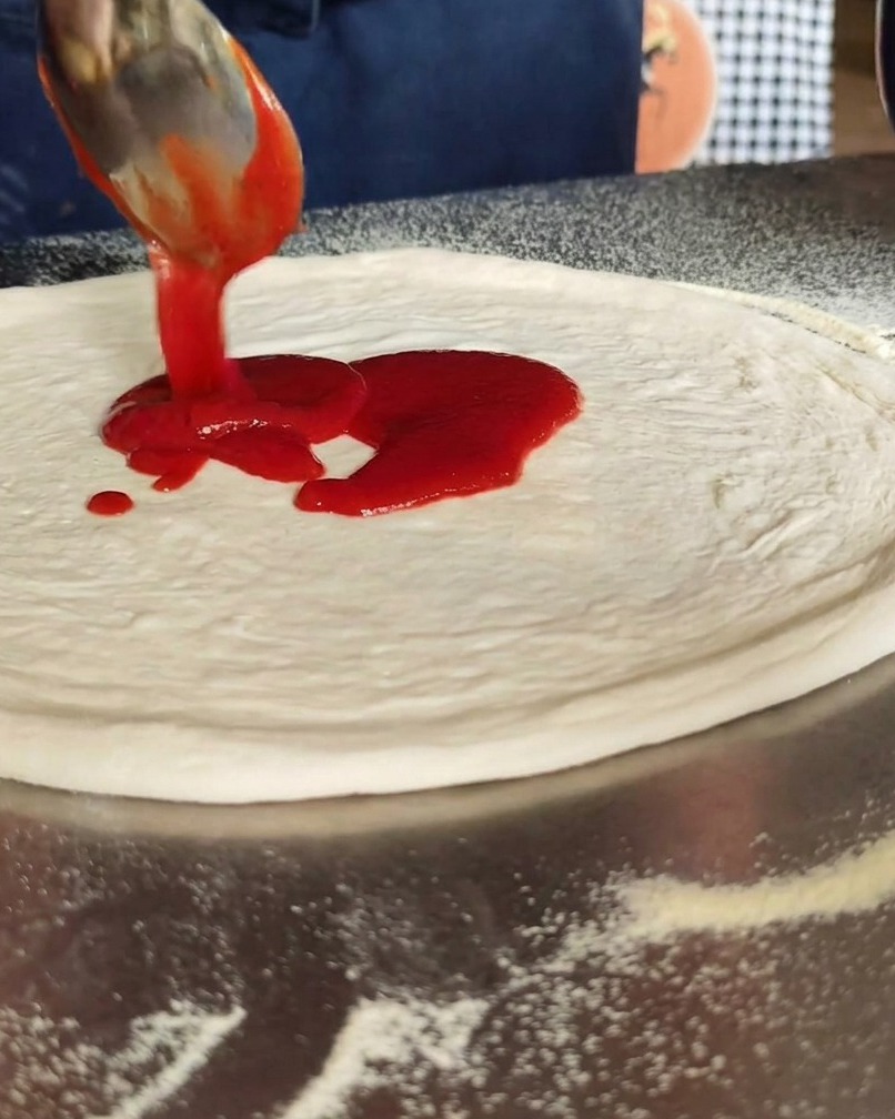 Salsa di pomodoro stesa sul disco di pasta.