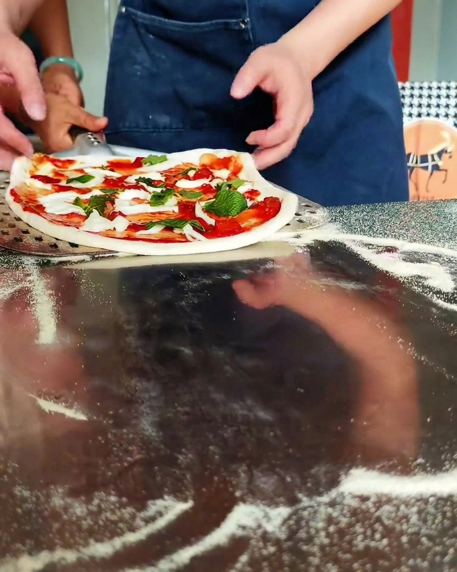 Pizza caricata su una pala metallica pronta per il forno.