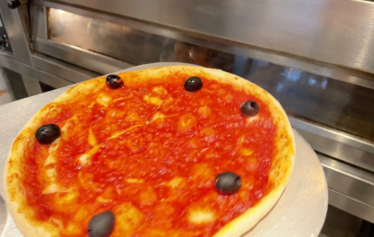 Una teglia per pizza inserita in un forno caldo per la cottura.