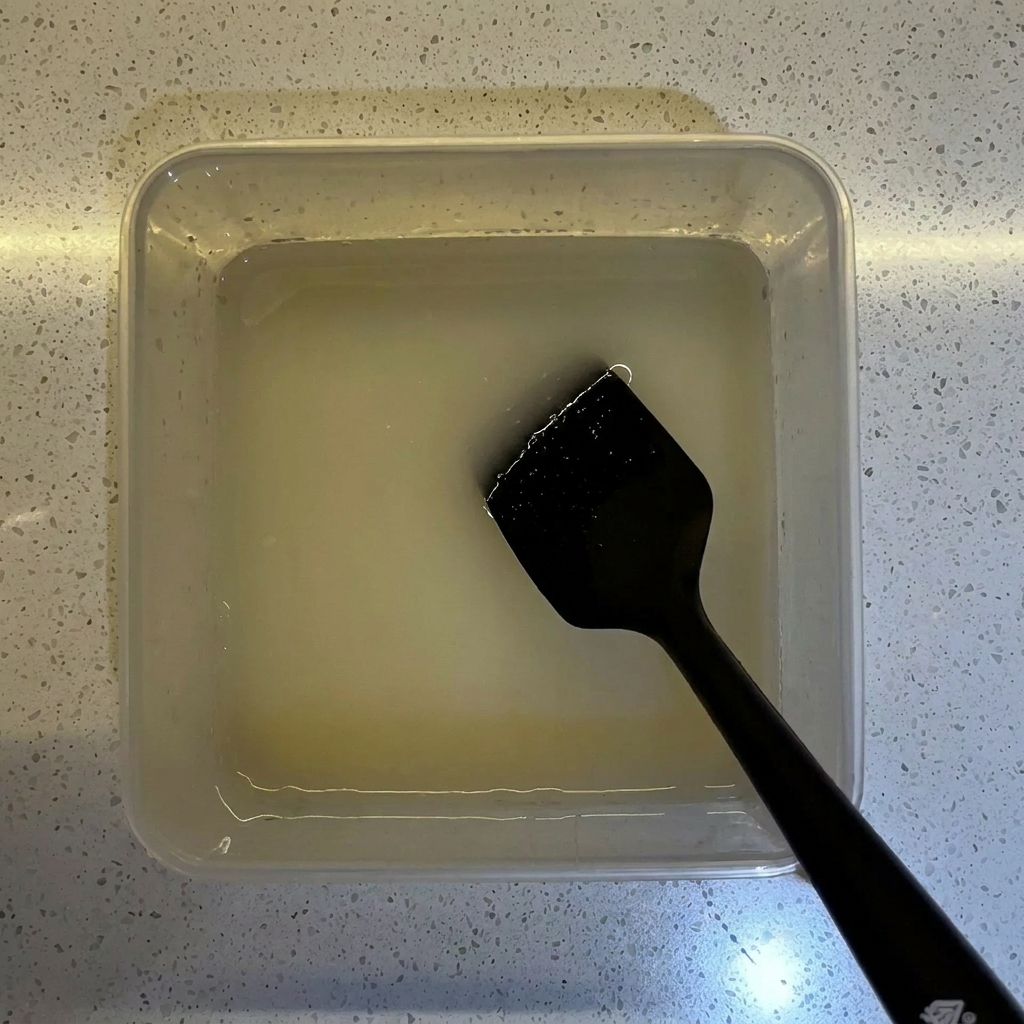 Farina versata in un contenitore trasparente contenente la miscela di acqua e lievito preparata.