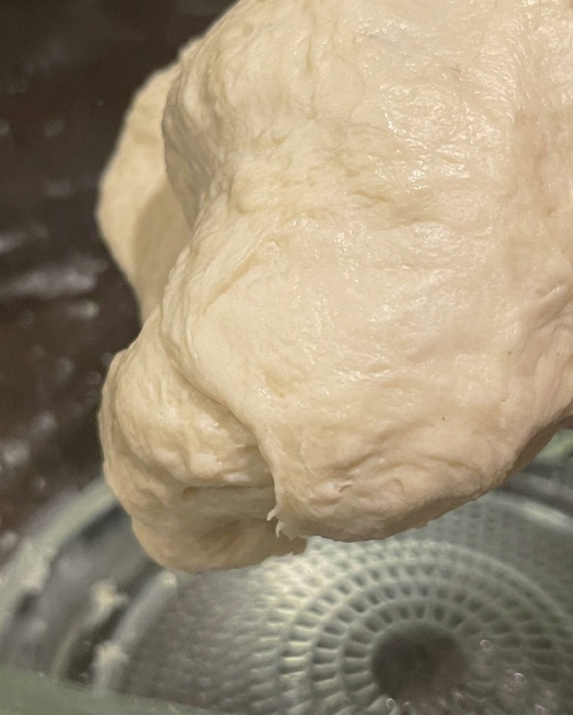 Una palla liscia ed elastica di impasto lavorato a mano, tenuta pronta per la lievitazione.