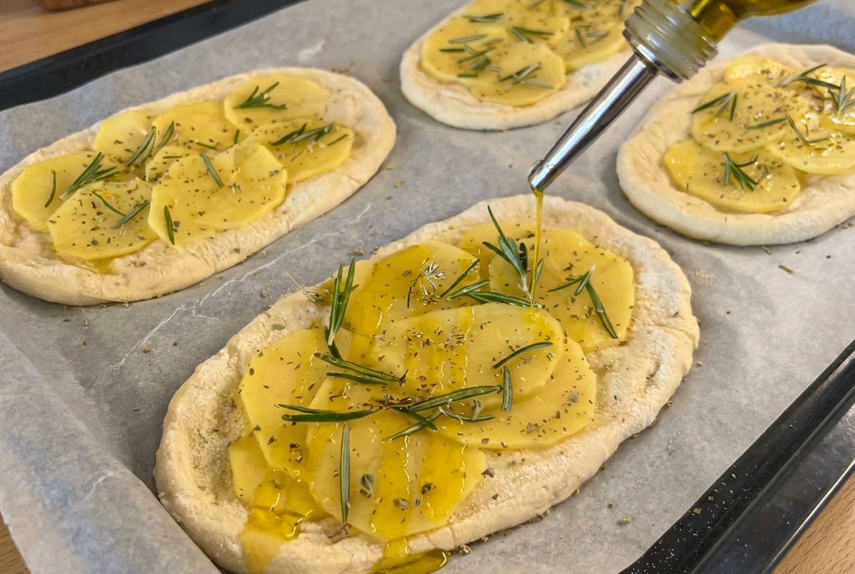 Olio doliva versato a filo sulle focaccine, pronte per essere infornate.