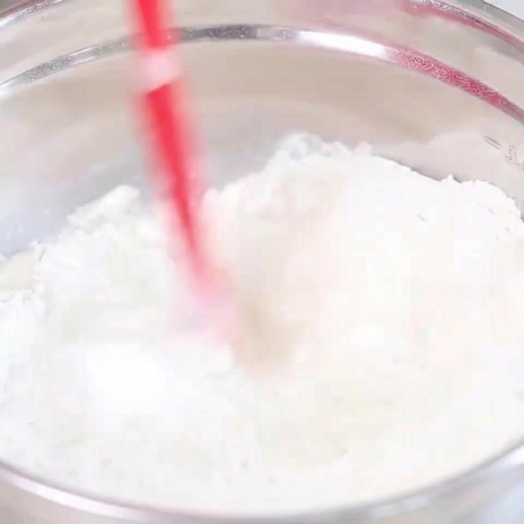 Farina e acqua mescolate in una ciotola dacciaio con una spatola per formare un impasto.