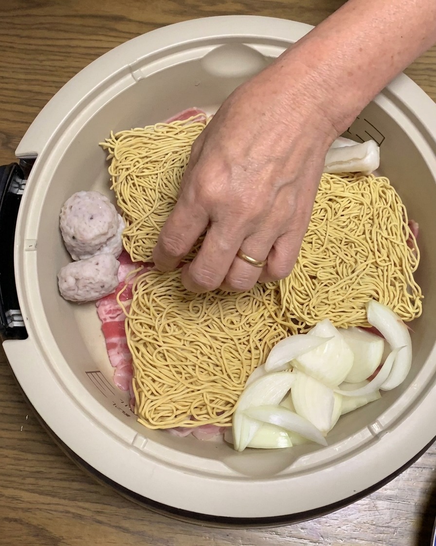 Tortini di riso e tofu fritto dorato aggiunti agli ingredienti assemblati nella pentola.