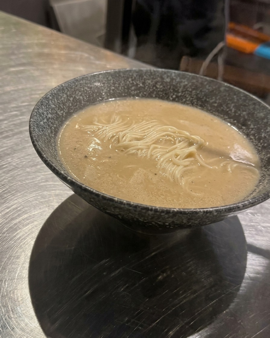 Un cucchiaio di carne macinata condita posizionato al centro di una ciotola di ramen.
