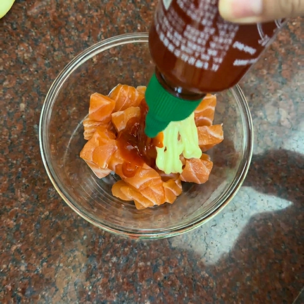 Cubetti di salmone in una ciotola di vetro pronti per essere conditi con salse.