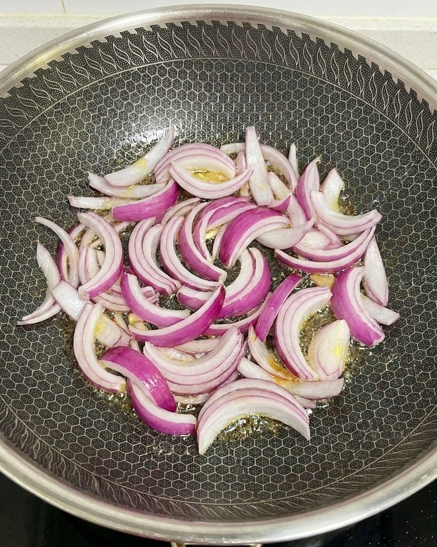 Fettine di cipolla rossa che saltano in un wok caldo con una trama esagonale e olio lucido.