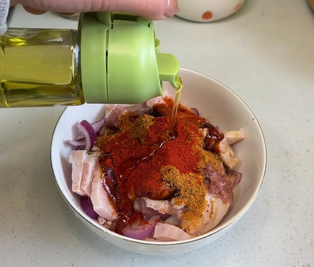 Olio vegetale trasparente versato da una bottiglia verde sulla miscela di pancetta e spezie.