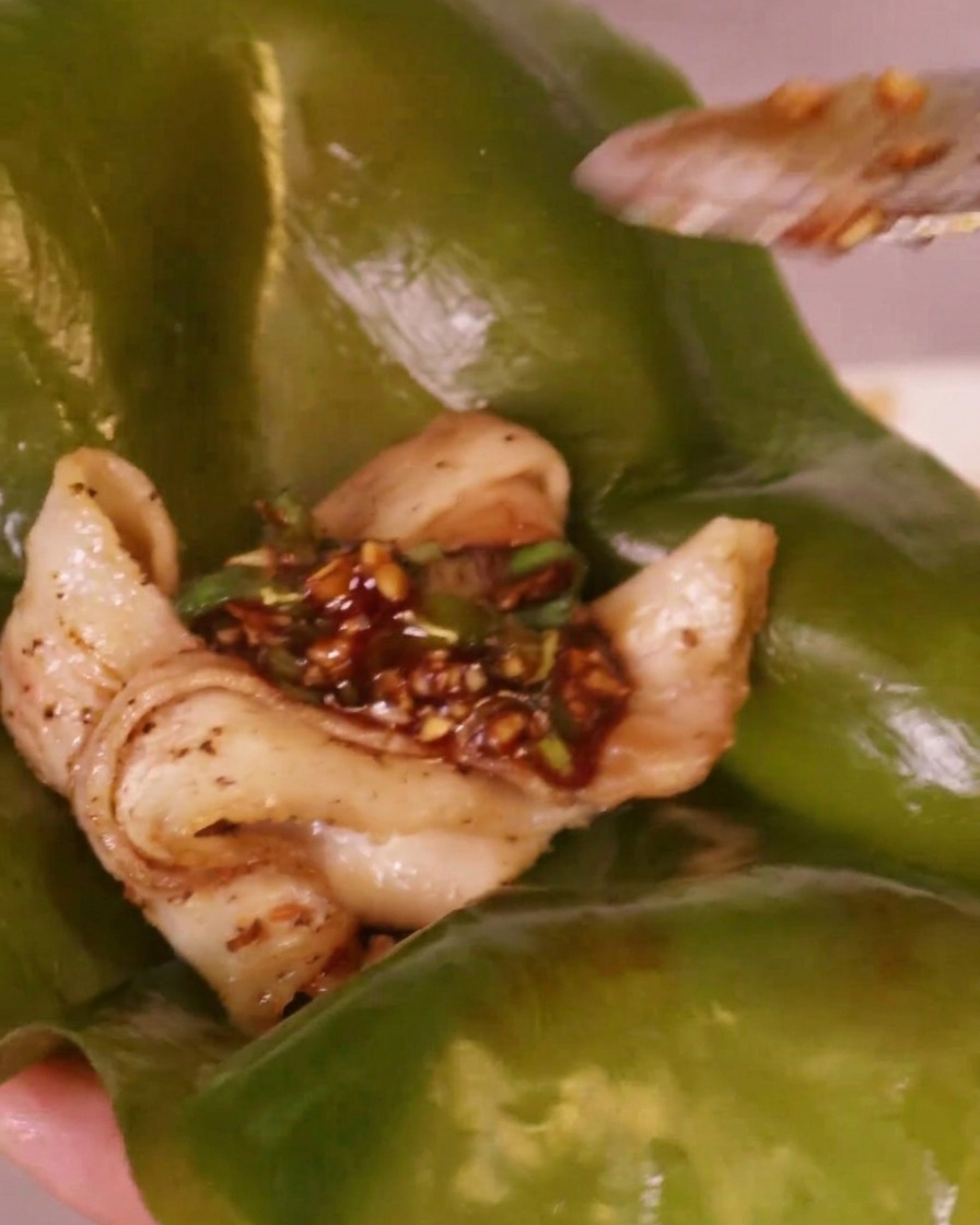 Salsa piccante al peperoncino rosso adagiata su un pezzo di pancetta di maiale grigliata posizionato su una foglia di alga kelp.