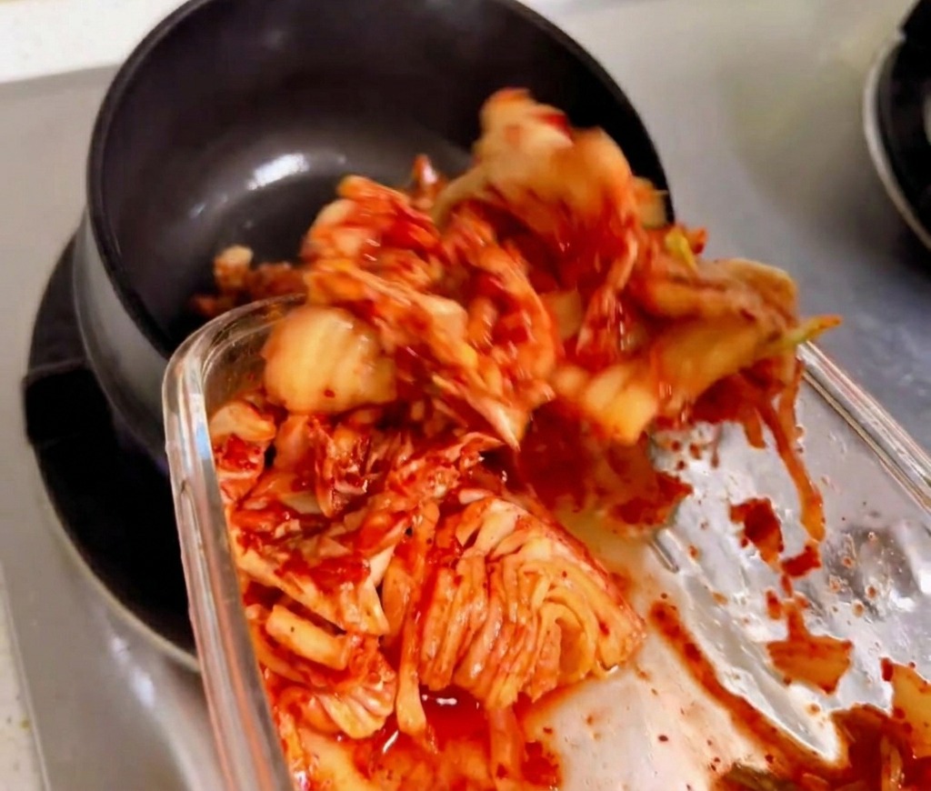 Kimchi a pezzi saltato in una tipica pentola di pietra nera su una fiamma a gas.