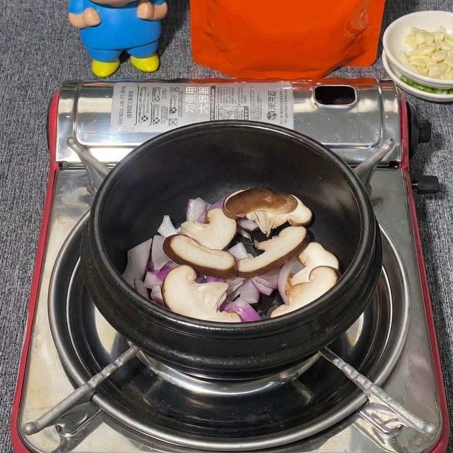 Una varietà di funghi, tra cui shiitake affettati e ciuffetti di funghi shimeji bianchi, disposti in una pentola di pietra nera sopra le cipolle.