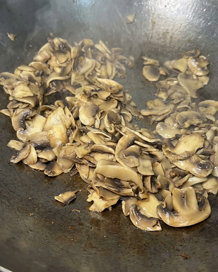 Fette di funghi saltate in padella, ormai ridotte di volume, dorate e quasi del tutto asciutte.