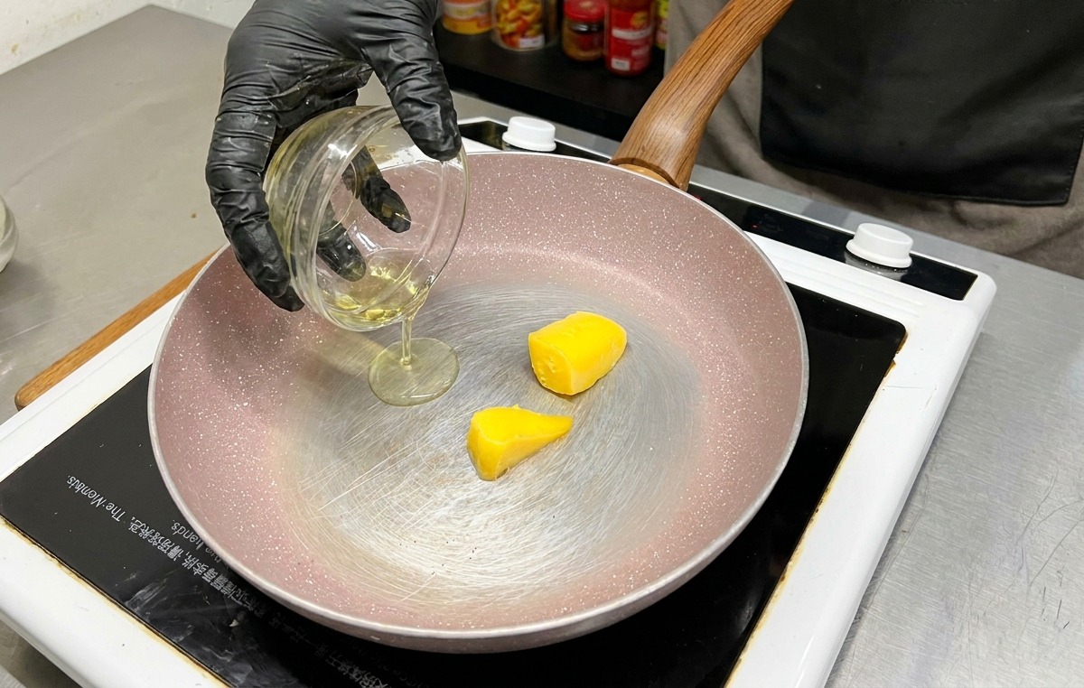 Due panetti di burro giallo in una padella mentre viene versato lolio doliva da una ciotolina di vetro.