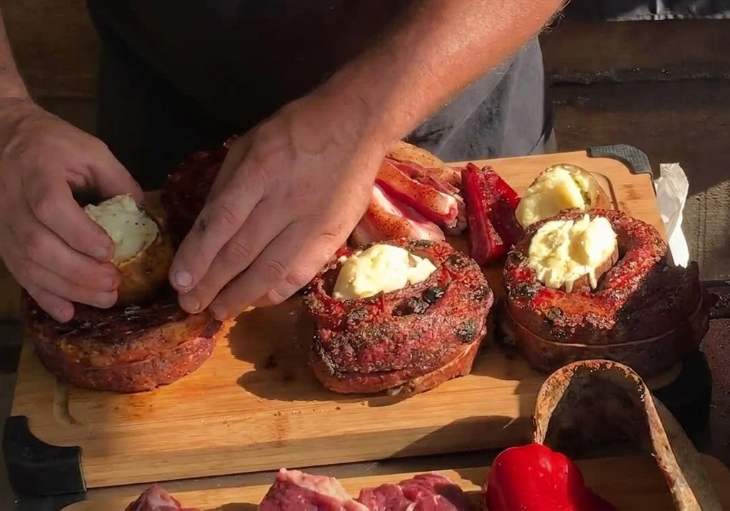 Mani che posizionano una patata intera arrostita nel centro vuoto di una striscia di costina cotta e circolare su un tagliere di legno.
