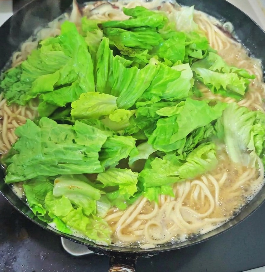 Delle floride verdure fresche dalle ampie foglie a cui fanno da cornice i germogli daglio appena spezzettati sopra i filamenti di pasta, proprio in mezzo al bollore.