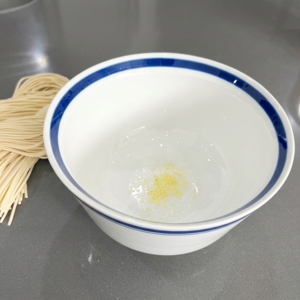 Pezzetti di aglio tritato dalle sfumature gialle sul fondo di una ciotola di ceramica bianca.