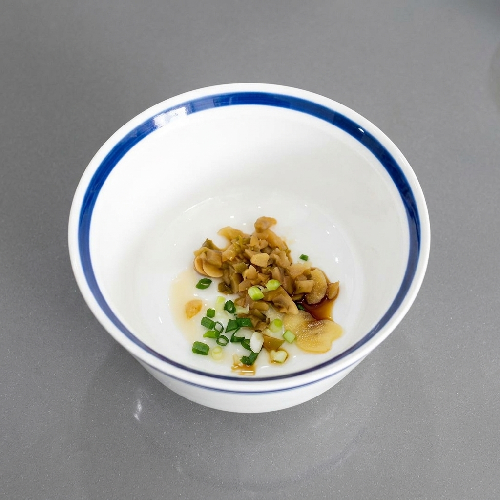 Cipollotti tritati mescolati con verdure in salamoia e aglio sul fondo di una ciotola di ceramica bianca.