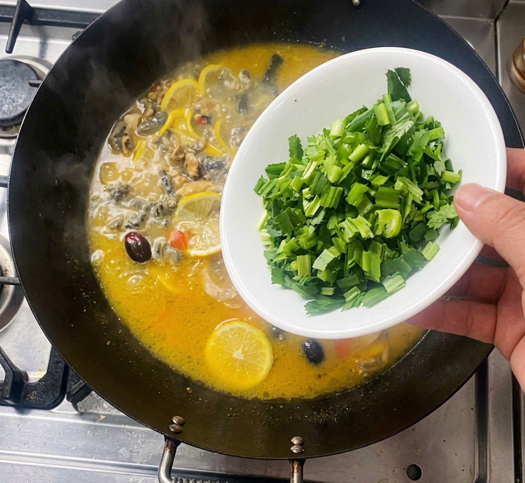 Una mano che versa coriandolo verde tritato da una ciotola bianca in un wok bollente con pollo e fette di limone.
