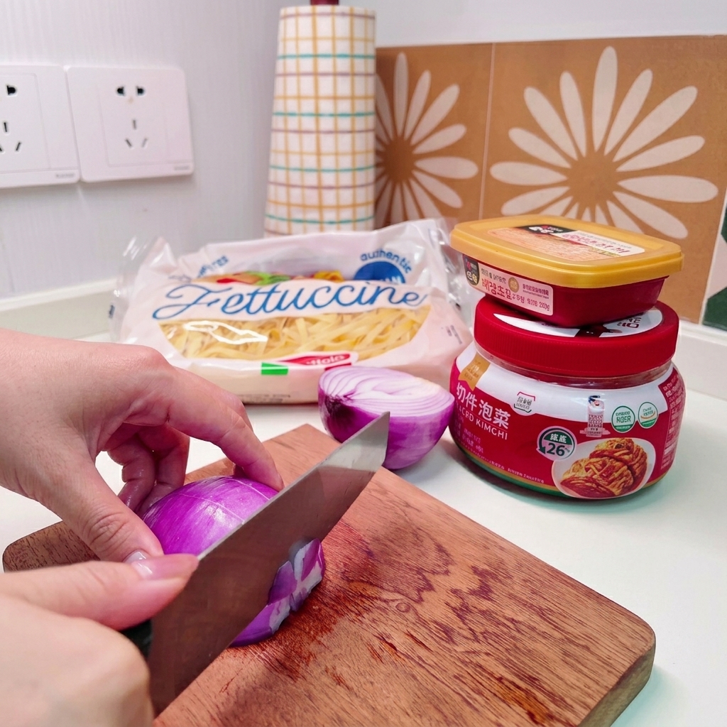 Primo piano di mani che usano un coltello per tagliare una cipolla rossa a cubetti piccoli su un tagliere di legno.
