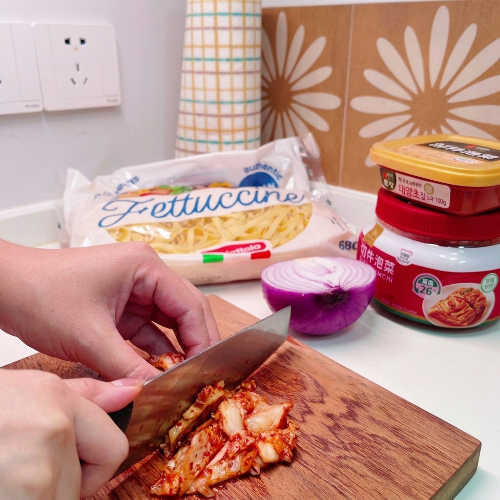 Un coltello che taglia un mucchietto di kimchi di cavolo su un tagliere di legno.