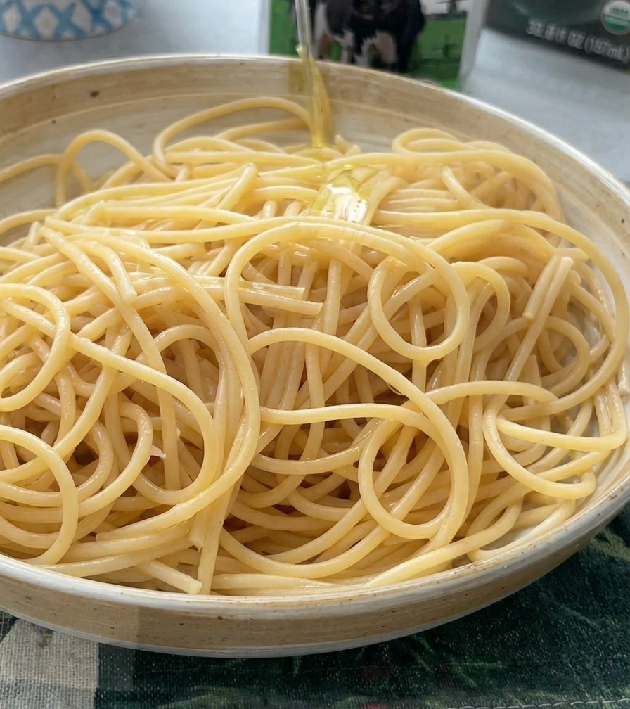 Primo piano di uno chef che sminuzza spicchi daglio fresco su un tagliere di legno con un grande coltello.