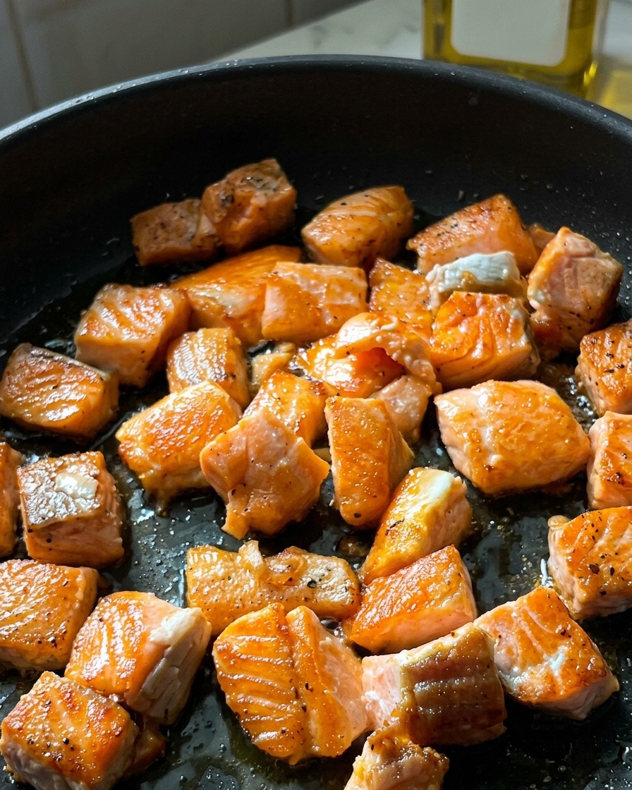 Cubetti di salmone in padella con una crosticina croccante e dorata sulle superfici scottate.