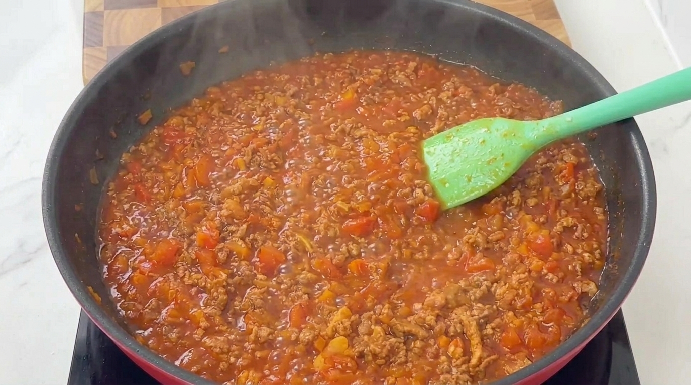 Un ricco ragù alla bolognese che sobbolle lentamente, denso di carne macinata e polpa di pomodoro.