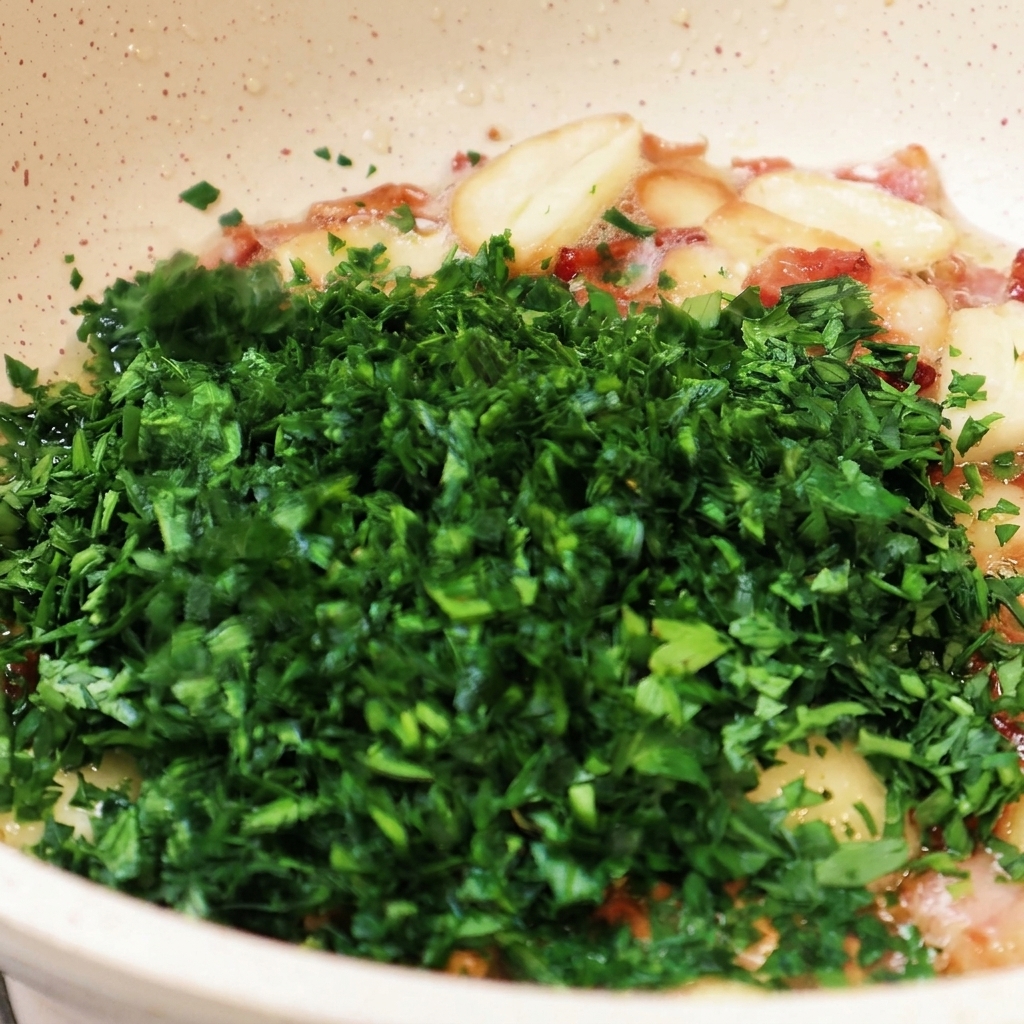 Una generosa manciata di prezzemolo verde tritato finemente viene aggiunta alla padella con laglio e il bacon soffritti.