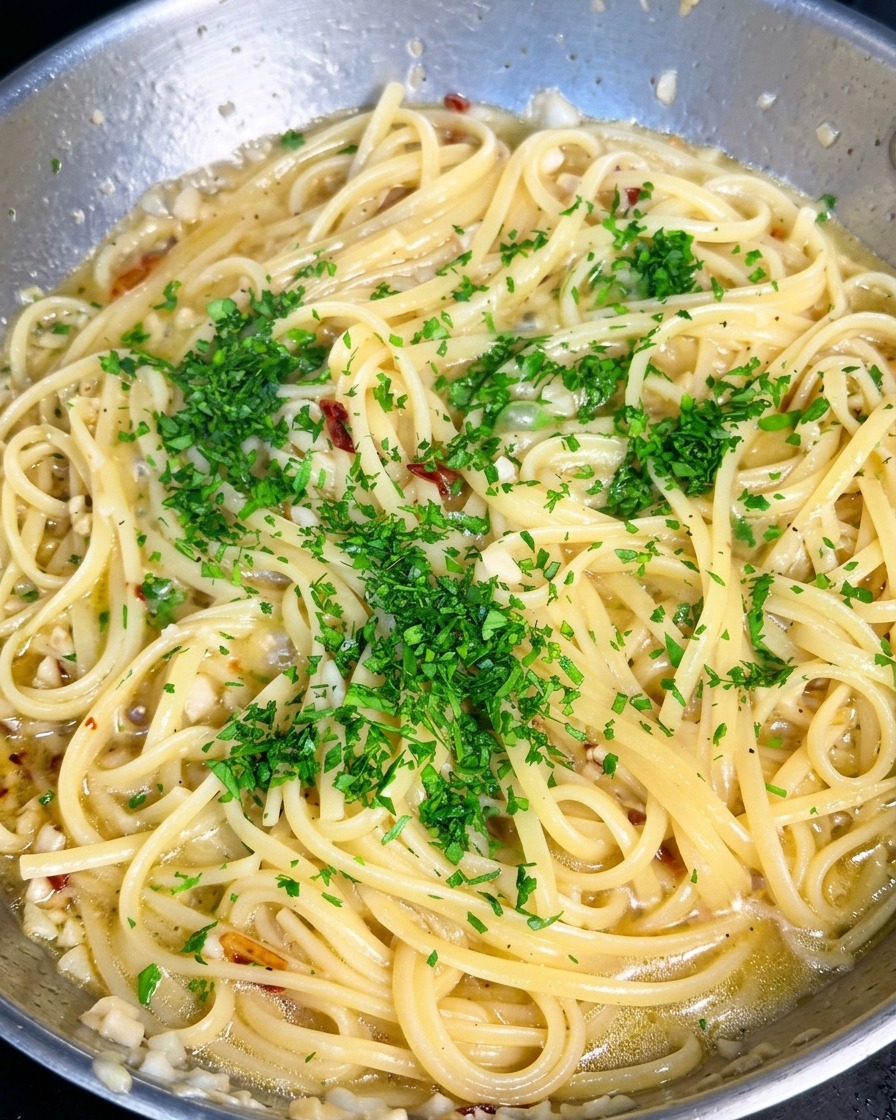 Prezzemolo verde tritato fresco viene sparso sopra una padella di pasta aglio e olio.