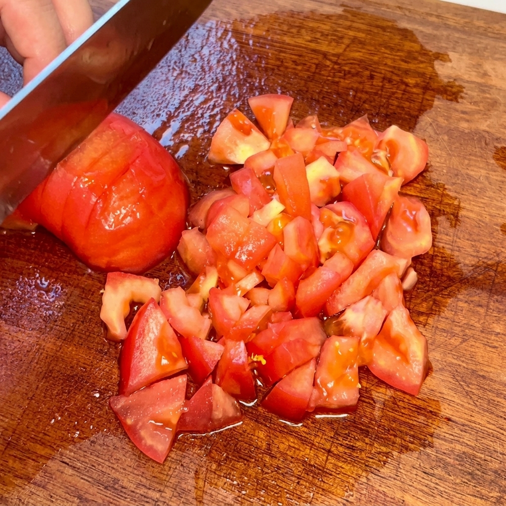 Pomodoro pelato tagliato a piccoli cubetti su un tagliere di legno.