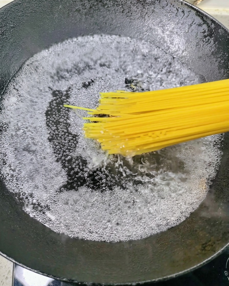 Spaghetti crudi immersi in una pentola di acqua che bolle vigorosamente.