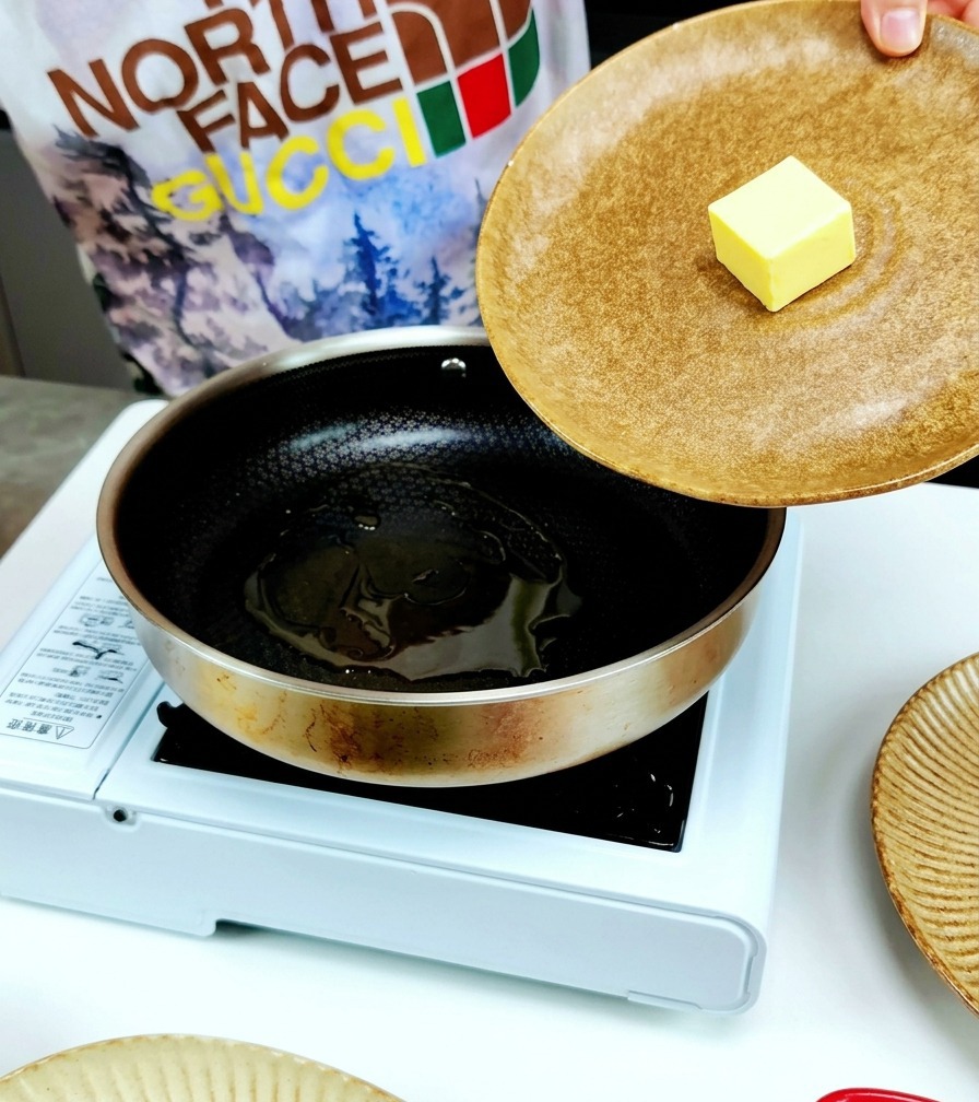 Una noce di burro aggiunta in una padella dacciaio insieme a un filo dolio doliva.