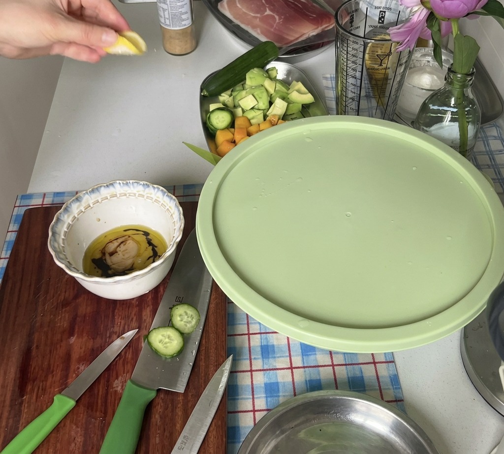 Una mano che spreme il succo di uno spicchio di limone in una ciotola con gli ingredienti del condimento.