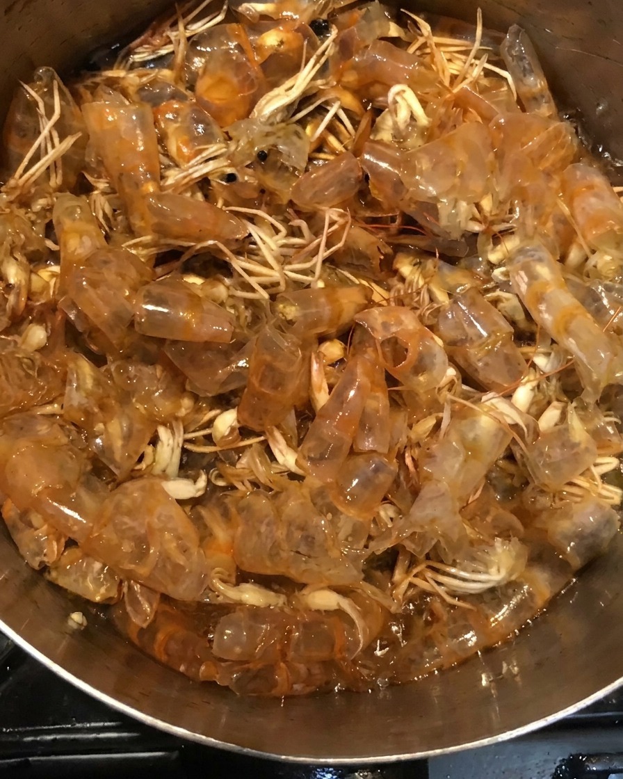 I gusci dei gamberi che sobbollono nel liquido scuro allinterno di una pentola.