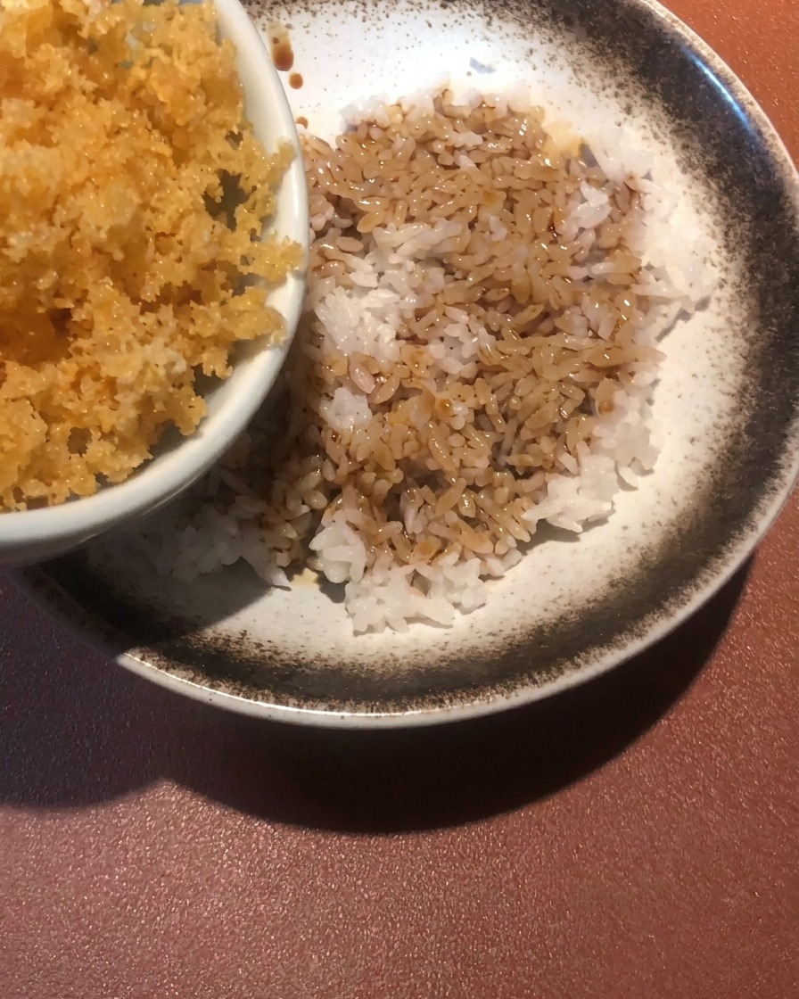 Briciole di pastella dorate sparse su una ciotola di riso condito.