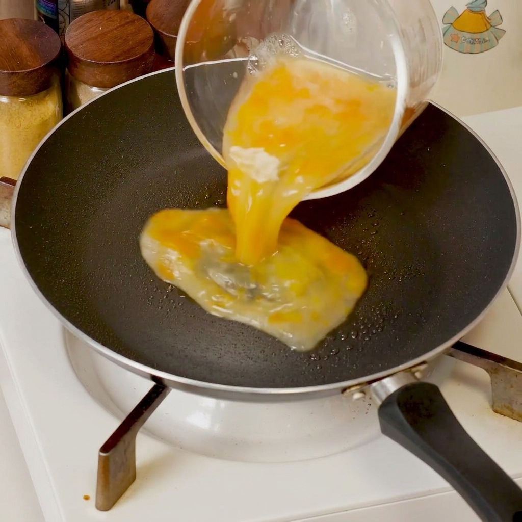 Uova sbattute che cuociono in una padella, spinte verso il centro con una spatola per formare morbidi grumi.