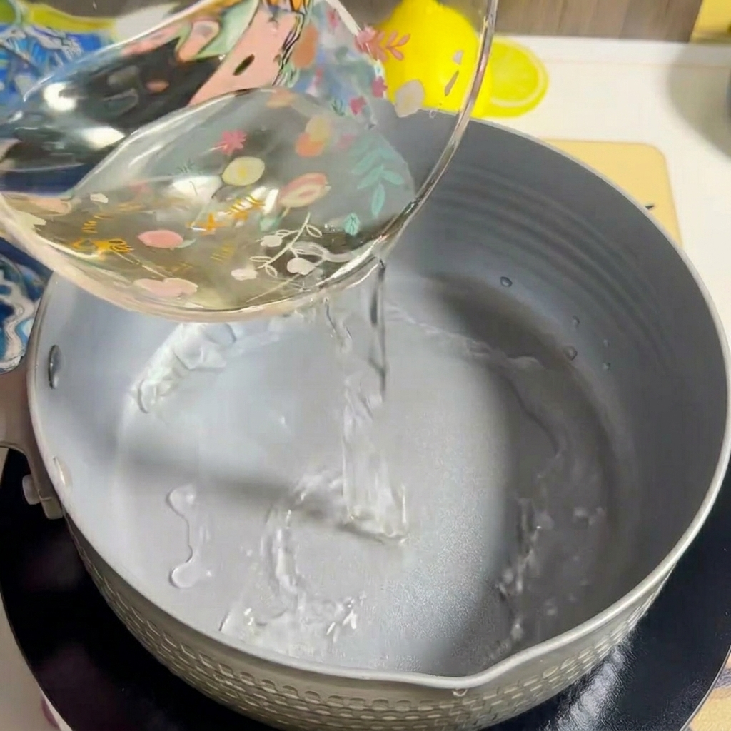 Acqua versata in una pentola grigia su un fornello.