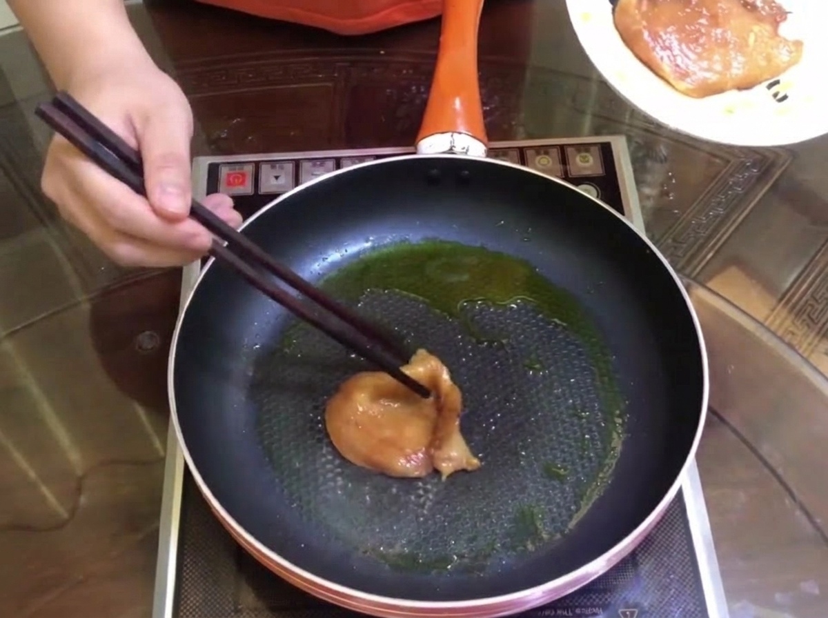Pezzi di carne marinata che rosolano in una padella con un filo dolio.