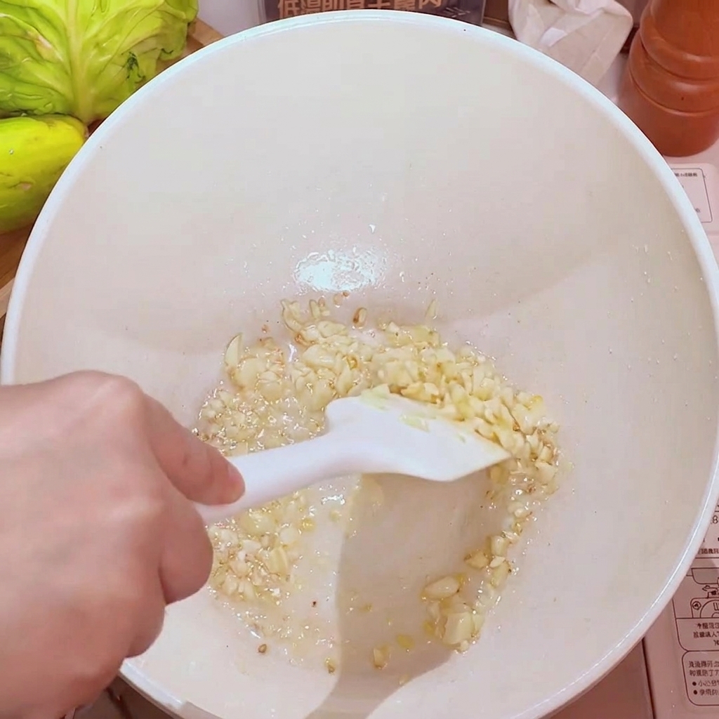 Aglio tritato che sfrigola in padella con olio, diventando dorato e aromatico.