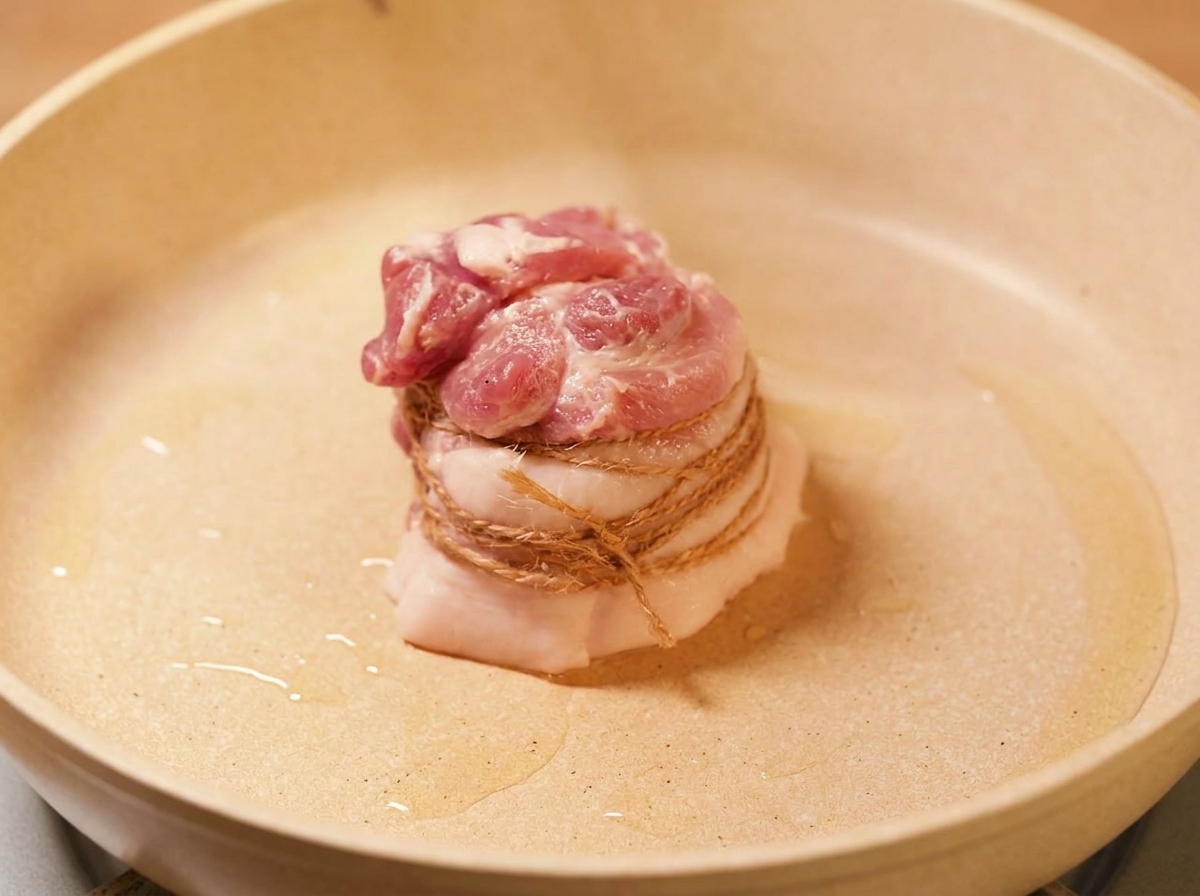 La pancetta legata che rosola in padella con olio caldo fino a doratura.