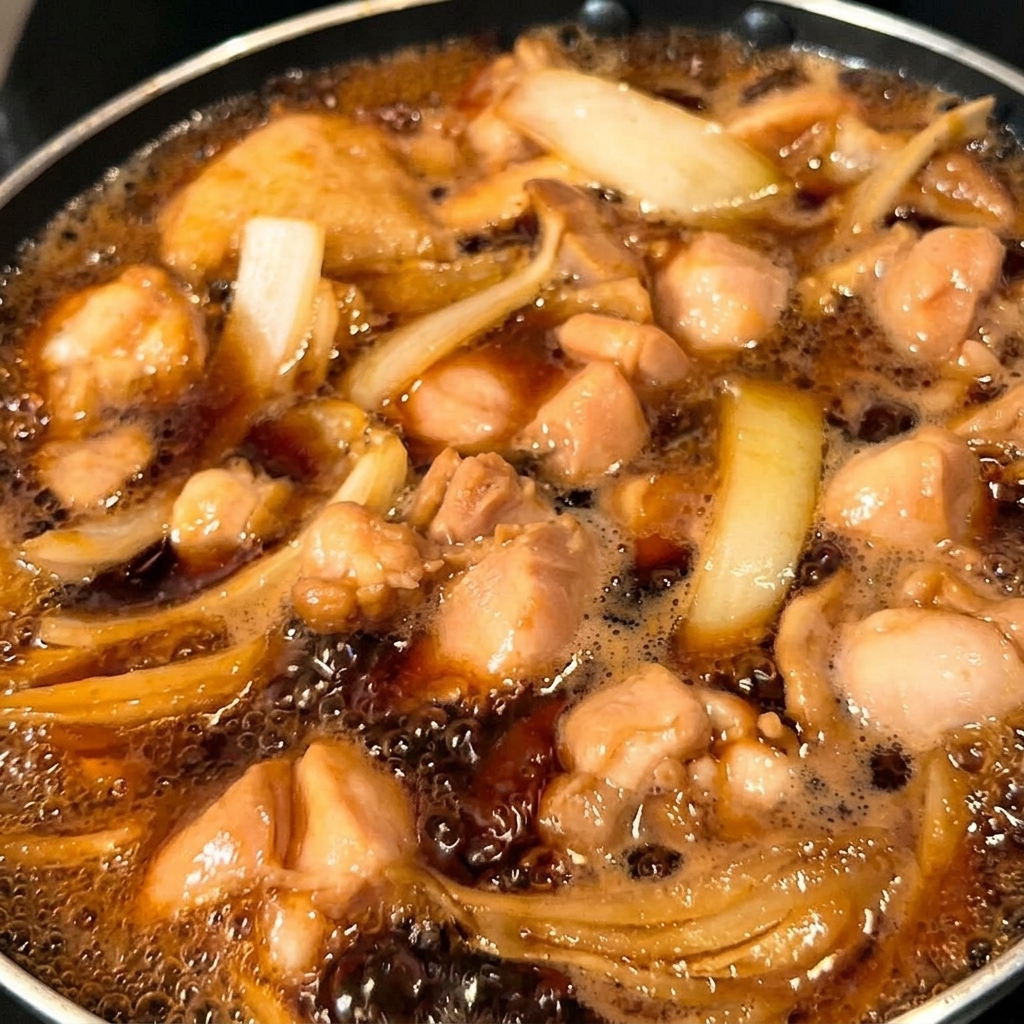 Metà del composto di uova versato nella padella sopra il pollo e le cipolle.