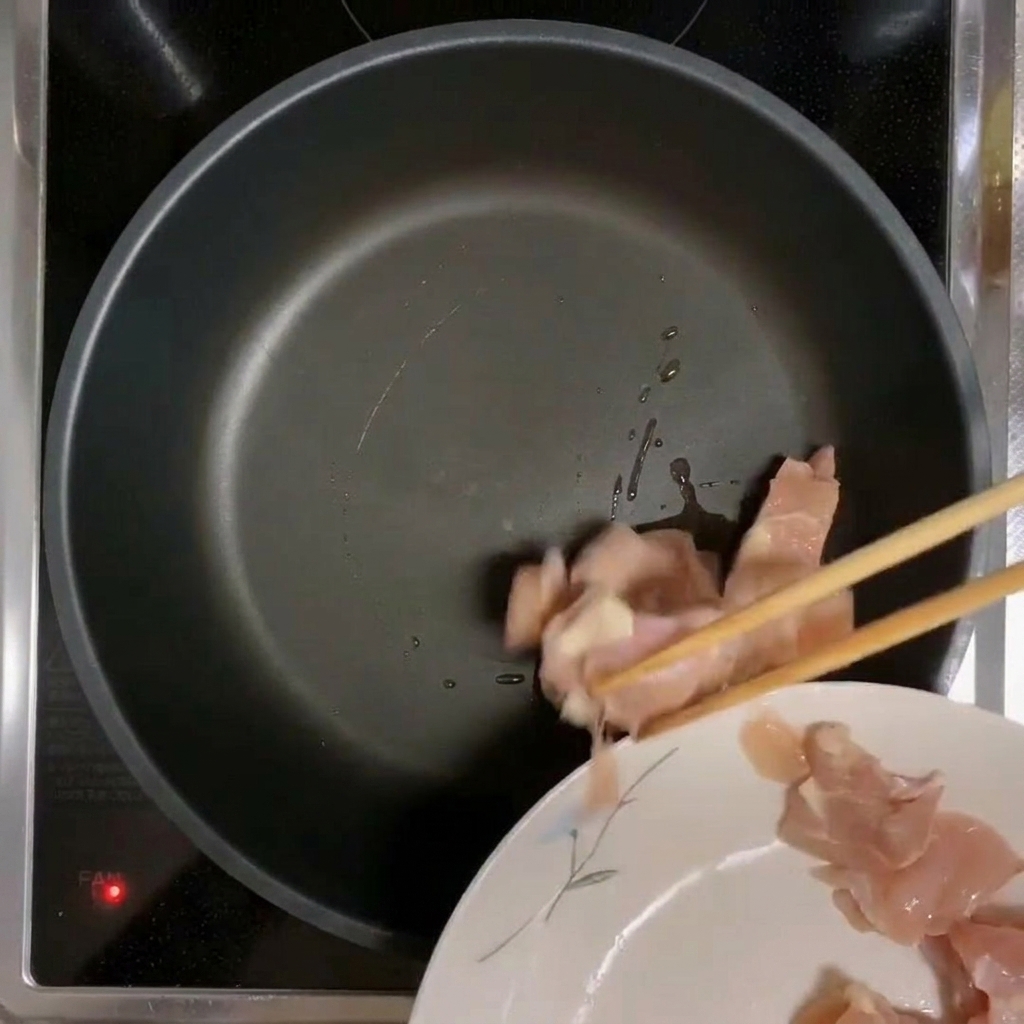 Pezzi di pollo messi in una padella preriscaldata e oliata.
