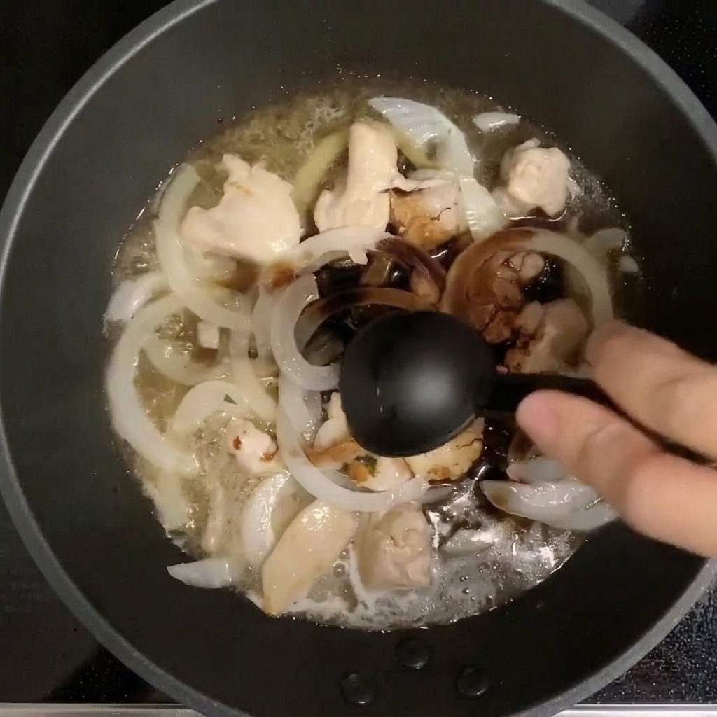 Cucchiaio che versa i condimenti in una padella con pollo e cipolla che sobbollono nel dashi.
